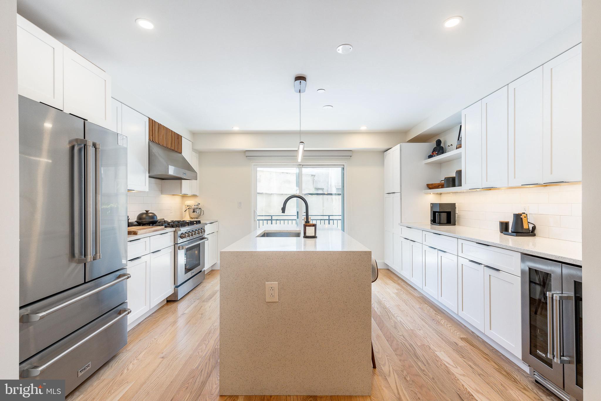 530 Reed Street Philadelphia, PA 19147 - Photo 9 of 57 a large kitchen with stainless steel appliances granite countertop a refrigerator oven a sink dishwasher and white cabinets with wooden floor