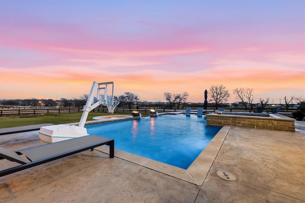 7751 Faught Road Northlake, TX 76226 - Photo 36 of 39 Expansive outdoor living area featuring a sparkling swimming pool, integrated spa, and a stone-clad fire pit