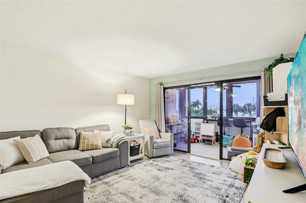 5855 Midnight Pass Road, Unit 227 Sarasota, FL 34242 - Photo 3 of 29 a living room with furniture a large window and gym equipment