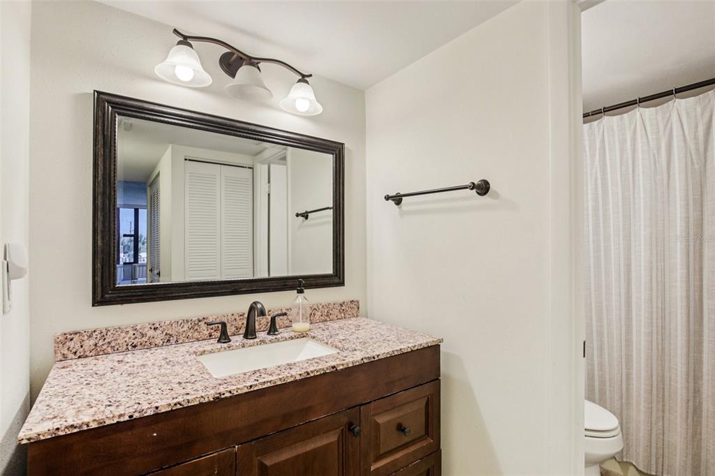 5855 Midnight Pass Road, Unit 227 Sarasota, FL 34242 - Photo 8 of 29 a bathroom with a granite countertop sink vanity mirror and toilet
