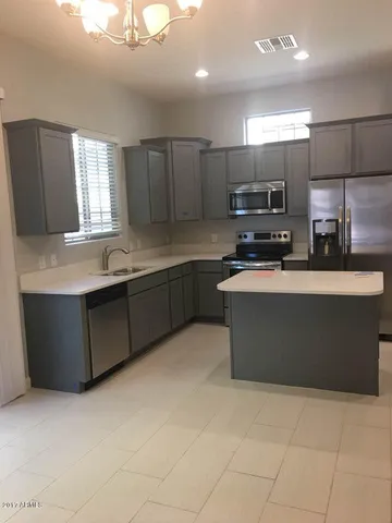 a kitchen with stainless steel appliances a sink a stove a microwave a center island and cabinets