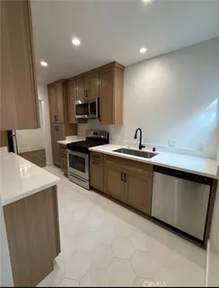a kitchen with stainless steel appliances a sink a stove a microwave a refrigerator a counter top and cabinets