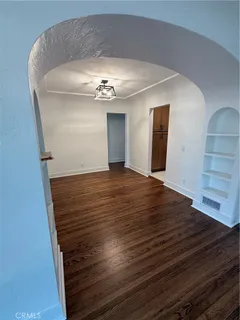 a view of an empty room with wooden floor and staircase