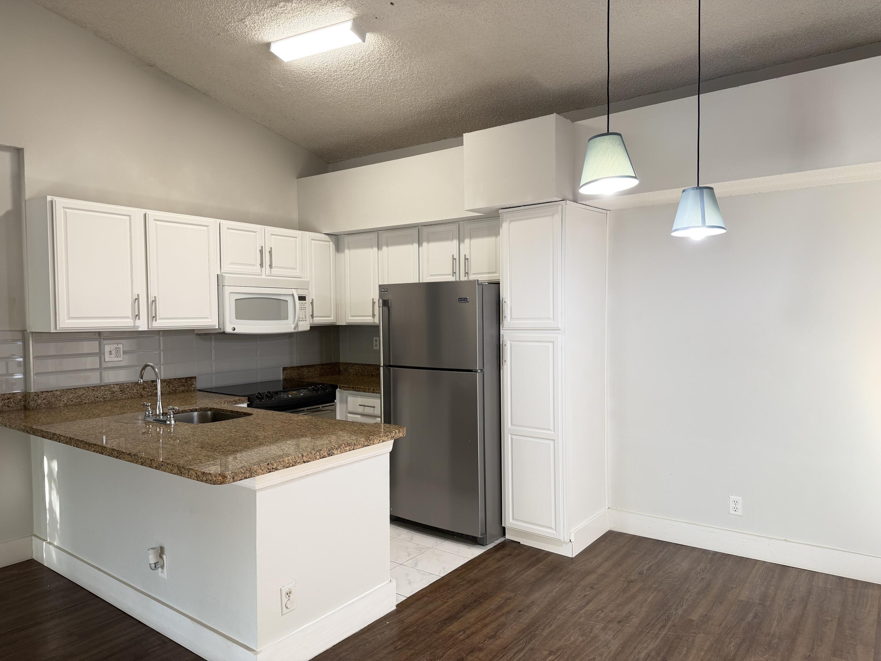 921 Lyons Road, Unit 3205 Coconut Creek, FL 33063 - Photo 3 of 17 a kitchen with a sink a refrigerator and cabinets