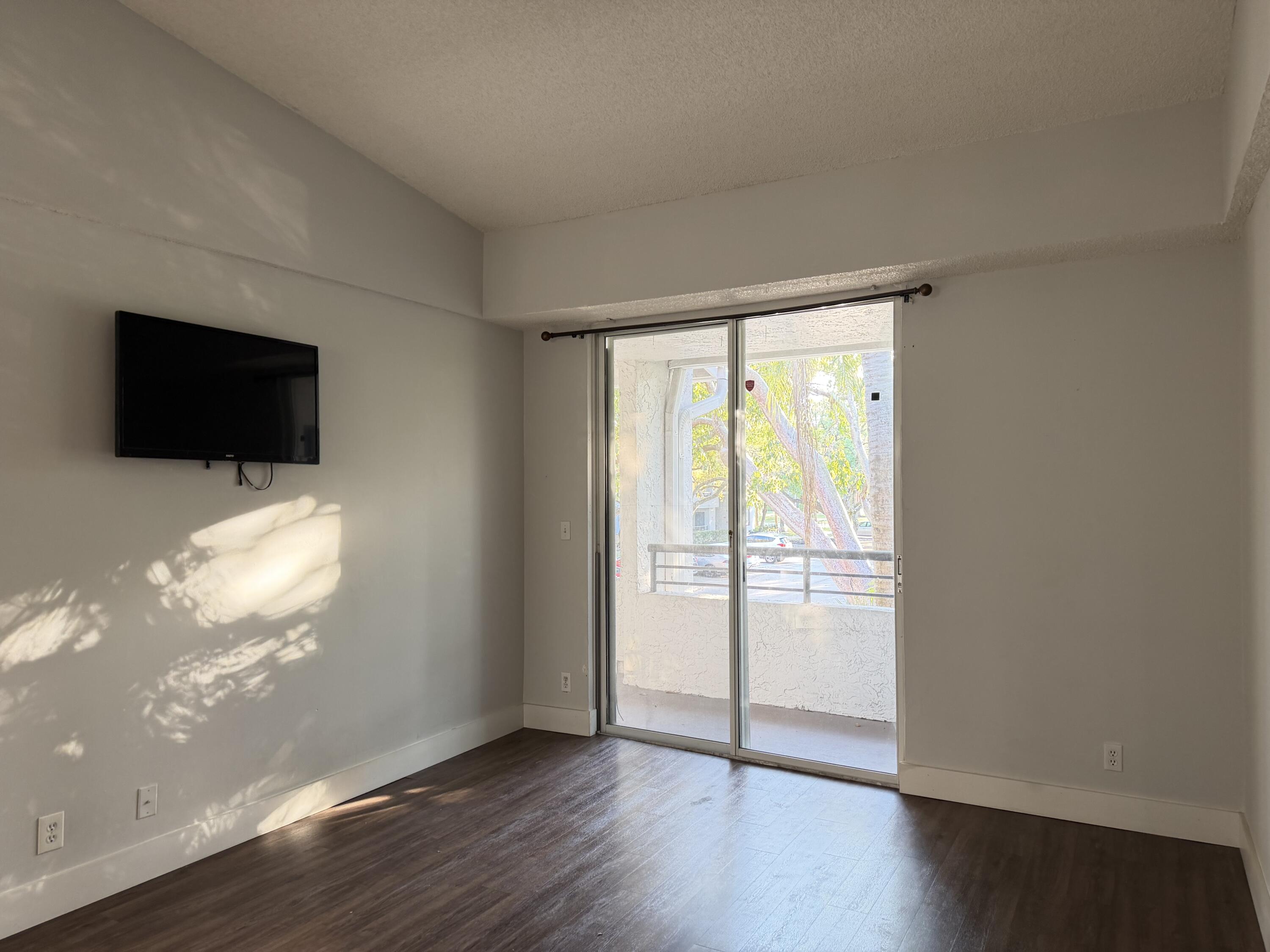 921 Lyons Road, Unit 3205 Coconut Creek, FL 33063 - Photo 4 of 17 a view of an empty room with wooden floor and a window