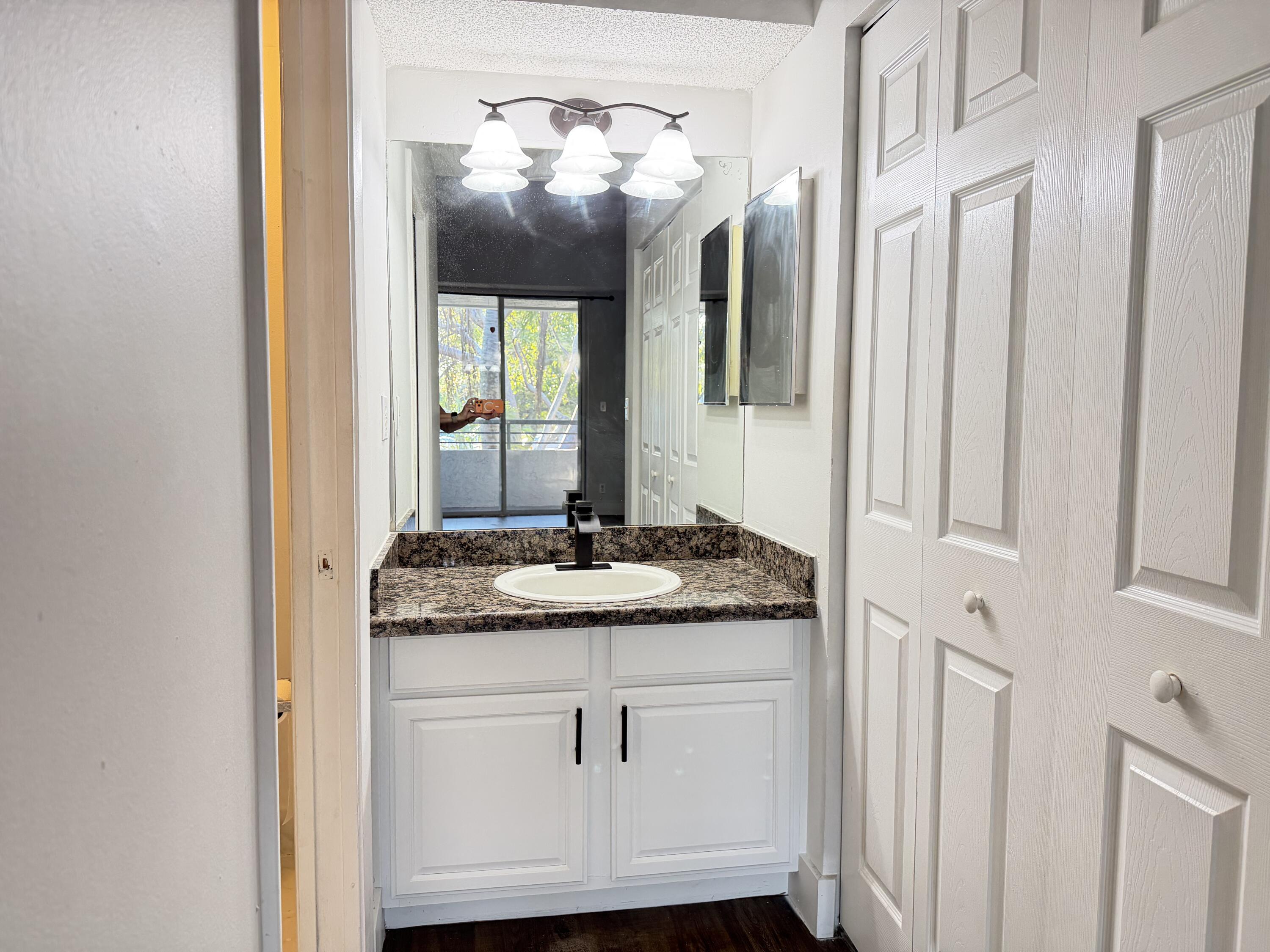 921 Lyons Road, Unit 3205 Coconut Creek, FL 33063 - Photo 6 of 17 a bathroom with a granite countertop sink and a mirror