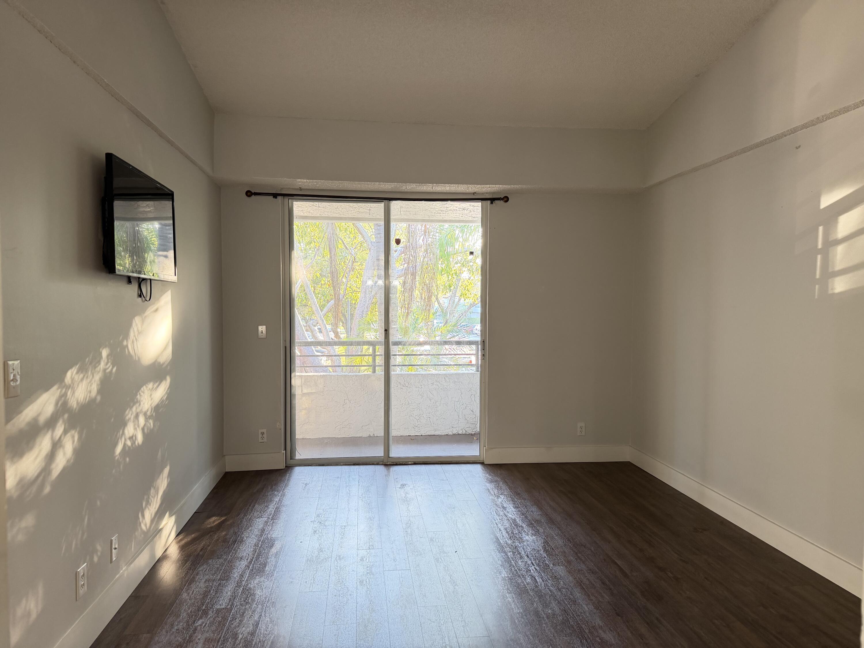 921 Lyons Road, Unit 3205 Coconut Creek, FL 33063 - Photo 8 of 17 an empty room with wooden floor and windows