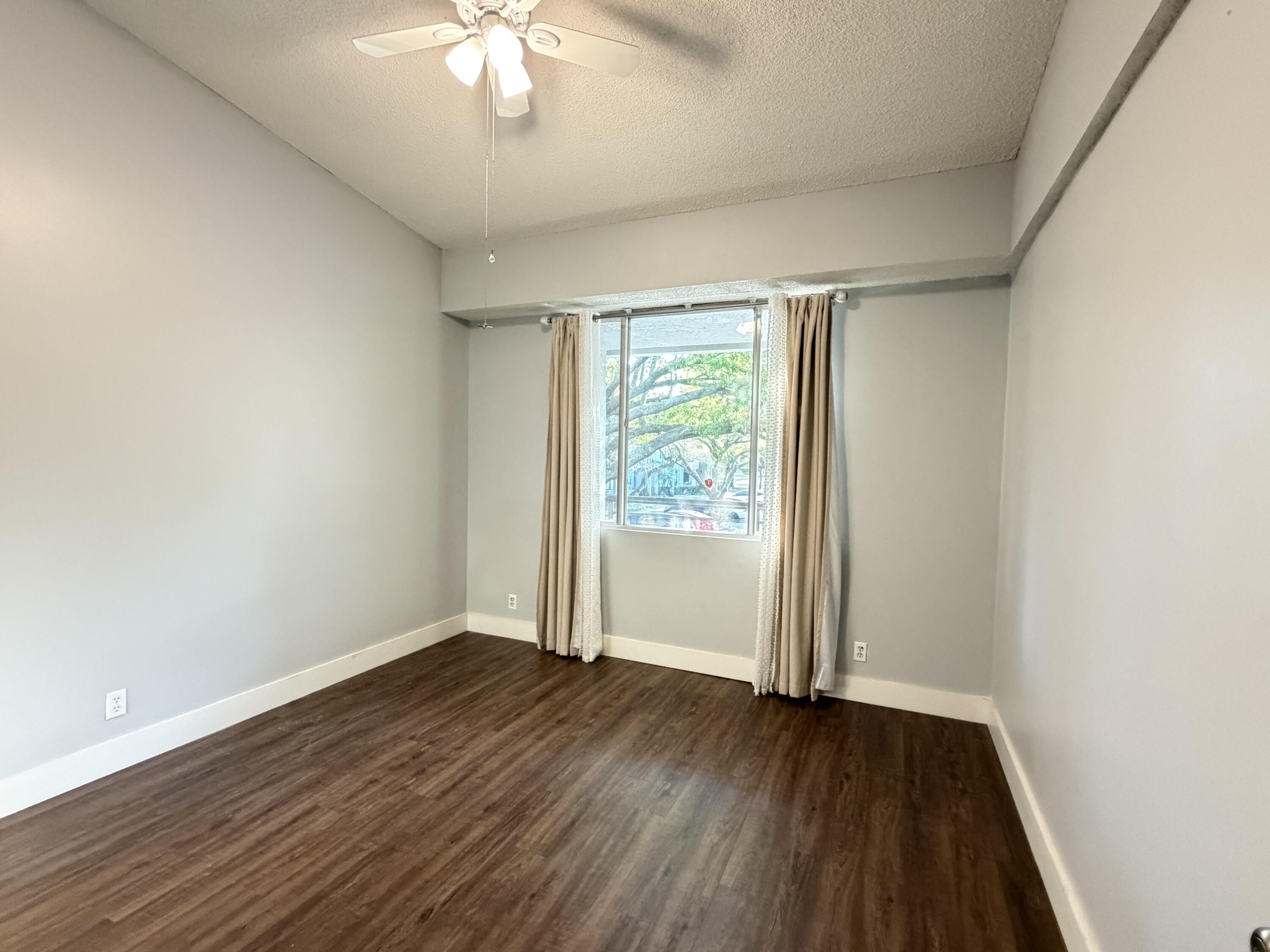 921 Lyons Road, Unit 3205 Coconut Creek, FL 33063 - Photo 9 of 17 an empty room with wooden floor and windows