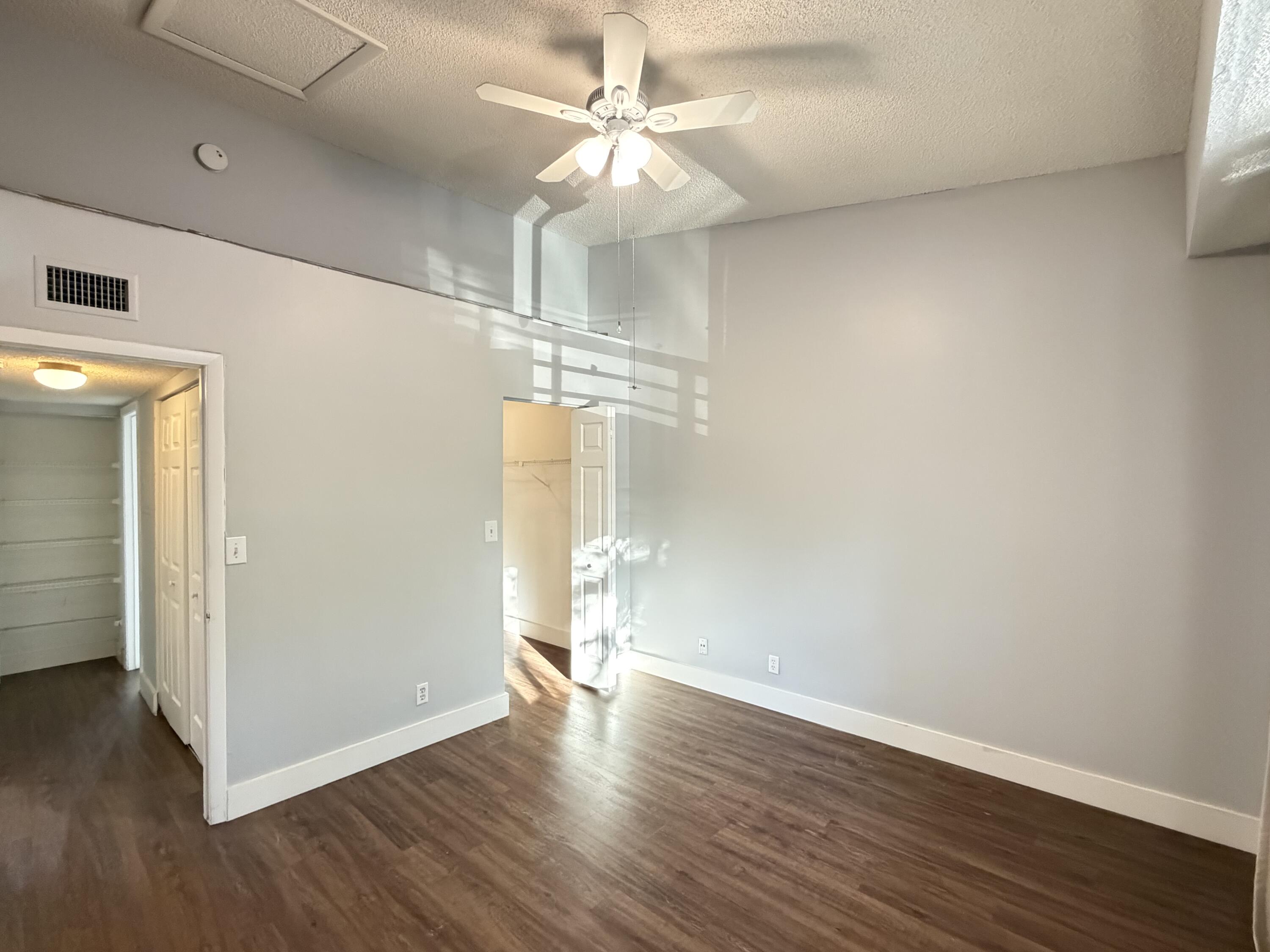 921 Lyons Road, Unit 3205 Coconut Creek, FL 33063 - Photo 10 of 17 an empty room with wooden floor and ceiling fan