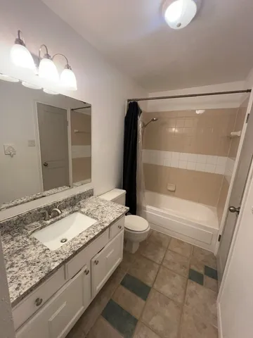 a bathroom with a granite countertop sink mirror and toilet