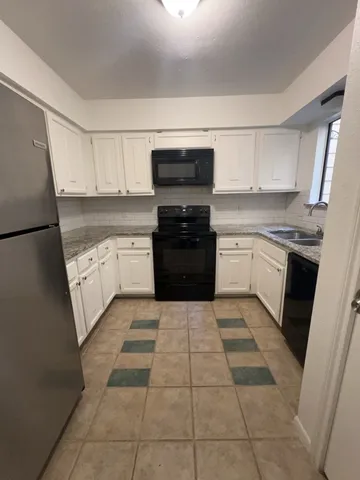 a kitchen with a sink a stove top oven and cabinets