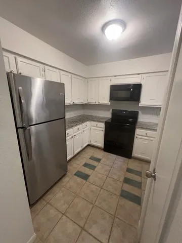 a kitchen with granite countertop a refrigerator and a sink