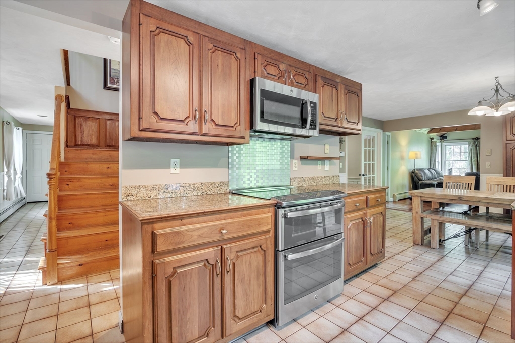 4 Stuart Road Rochester, MA 02770 - Photo 5 of 37 a kitchen with stainless steel appliances granite countertop a stove top oven microwave and cabinets