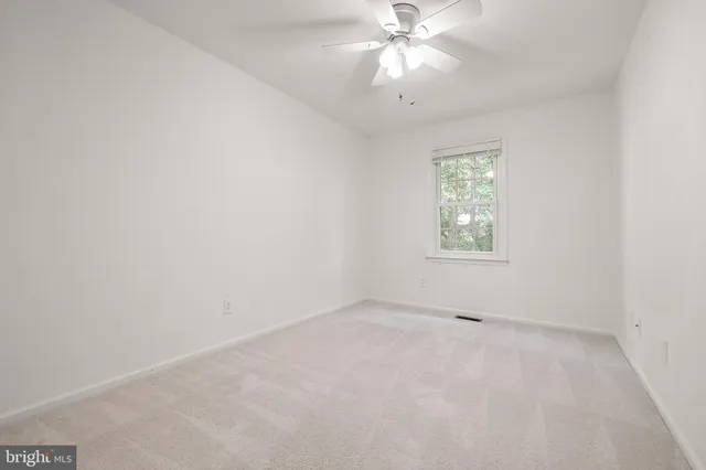an empty room with a window and a fan