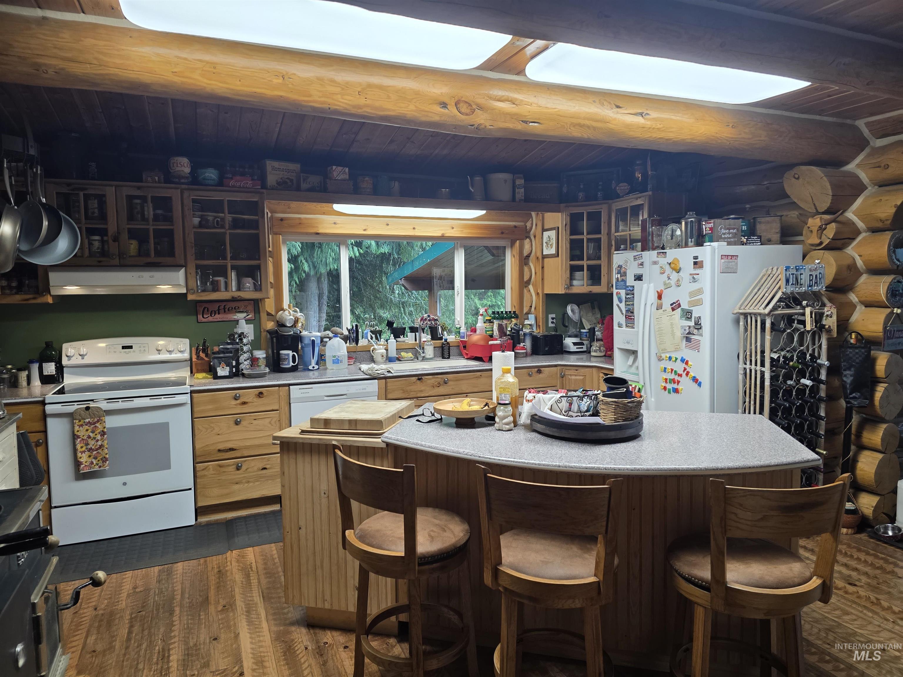 112 Three Forks Road Kamiah, ID 83536 - Photo 13 of 45 Kitchen featuring wood-finish flooring, natural wood cabinetry, a central island with bar seating, skylights, and a window overlooking exterior greenery