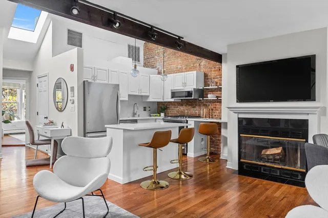 a living room with furniture a fireplace a flat screen tv and kitchen view