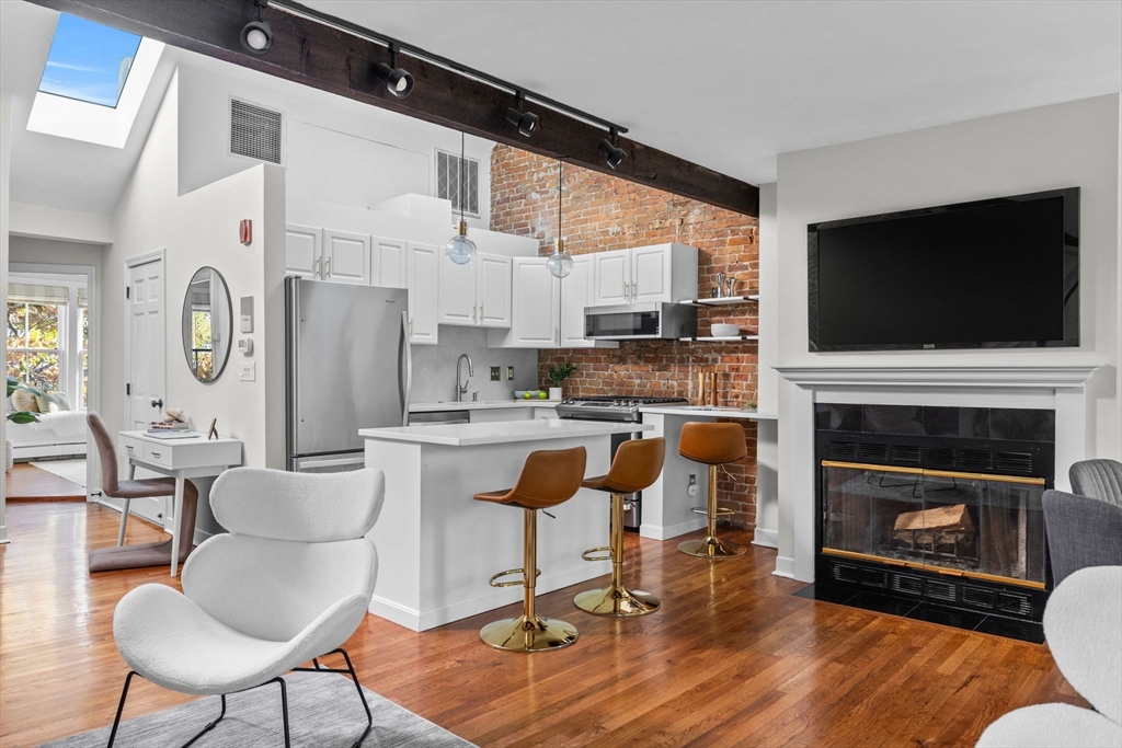 81 Waltham Street, Unit 6 Boston, MA 02118 - Photo 2 of 24 a living room with furniture a fireplace a flat screen tv and kitchen view