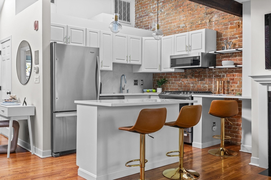 81 Waltham Street, Unit 6 Boston, MA 02118 - Photo 8 of 24 a kitchen with stainless steel appliances granite countertop a refrigerator a stove a sink a dining table and chairs with wooden floor