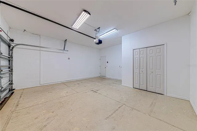 an empty room with chandelier fan and windows