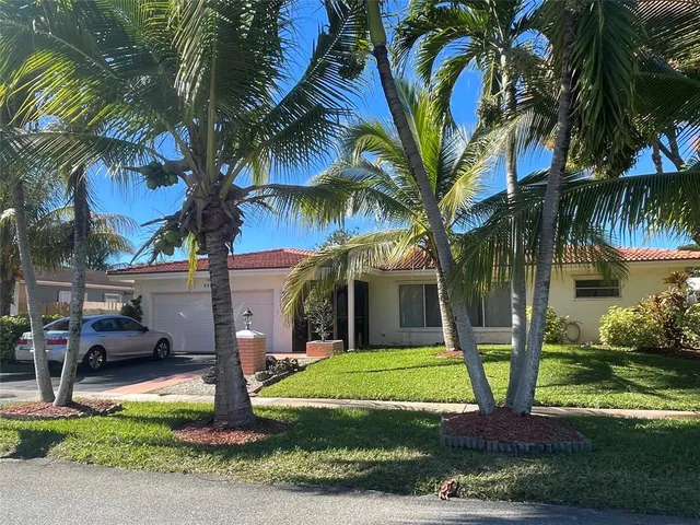 a view of a house with a yard and palm trees