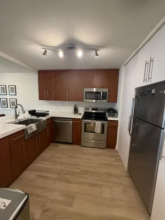 a kitchen with granite countertop stainless steel appliances a refrigerator a sink a stove top oven and a refrigerator