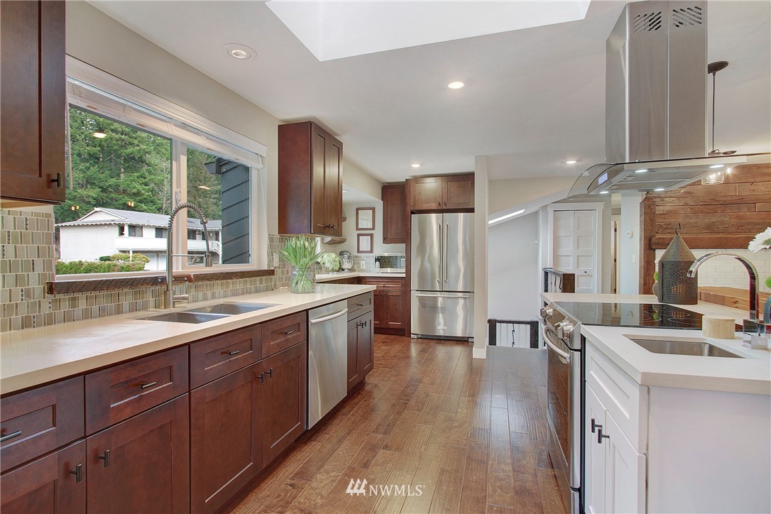15003 Southeast 138th Place Renton, WA 98059 - Photo 5 of 38 a kitchen with stainless steel appliances kitchen island granite countertop a sink stove and wooden cabinets