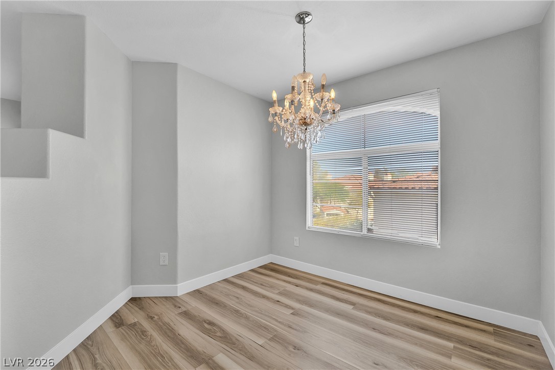 698 South Racetrack Road, Unit 1521 Henderson, NV 89015 - Photo 13 of 33 Elegant chandelier illumination over warm wood flooring creates an inviting dining space.