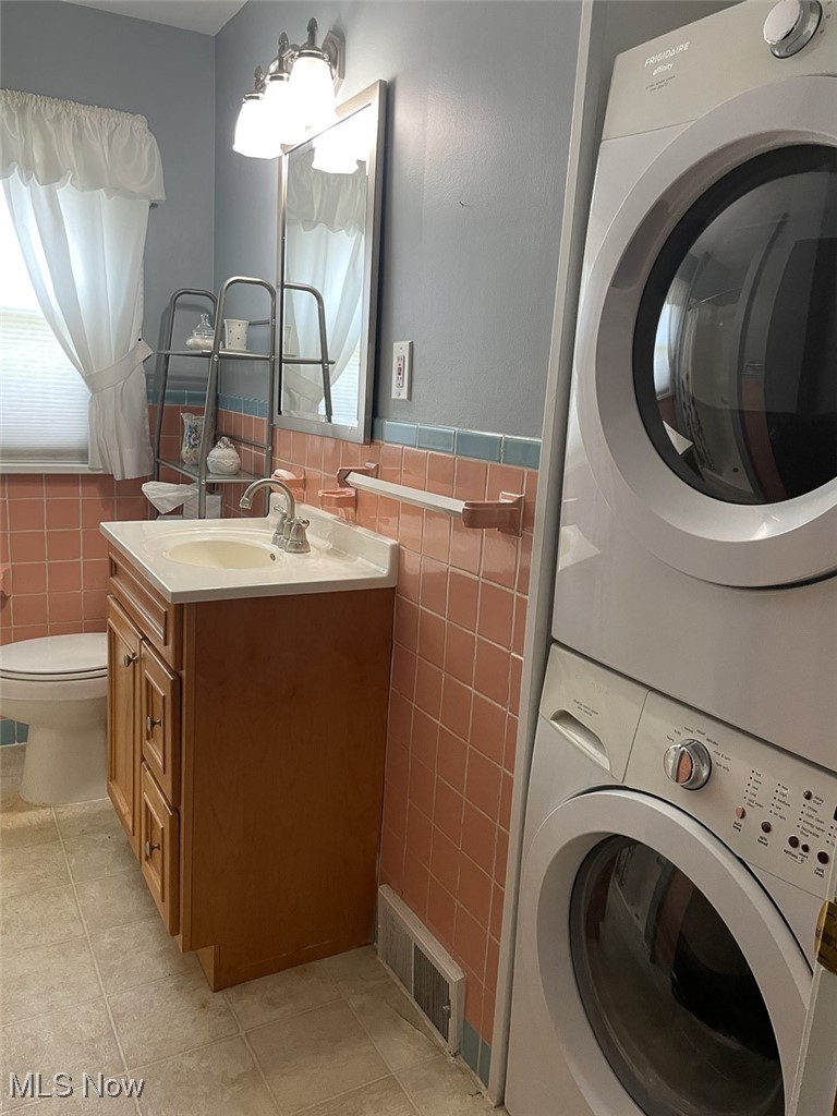4425 2nd Street Northwest Canton, OH 44708 - Photo 16 of 24 Bathroom with stacked washing machine and dryer, tile walls, tile patterned flooring, vanity, and wainscoting