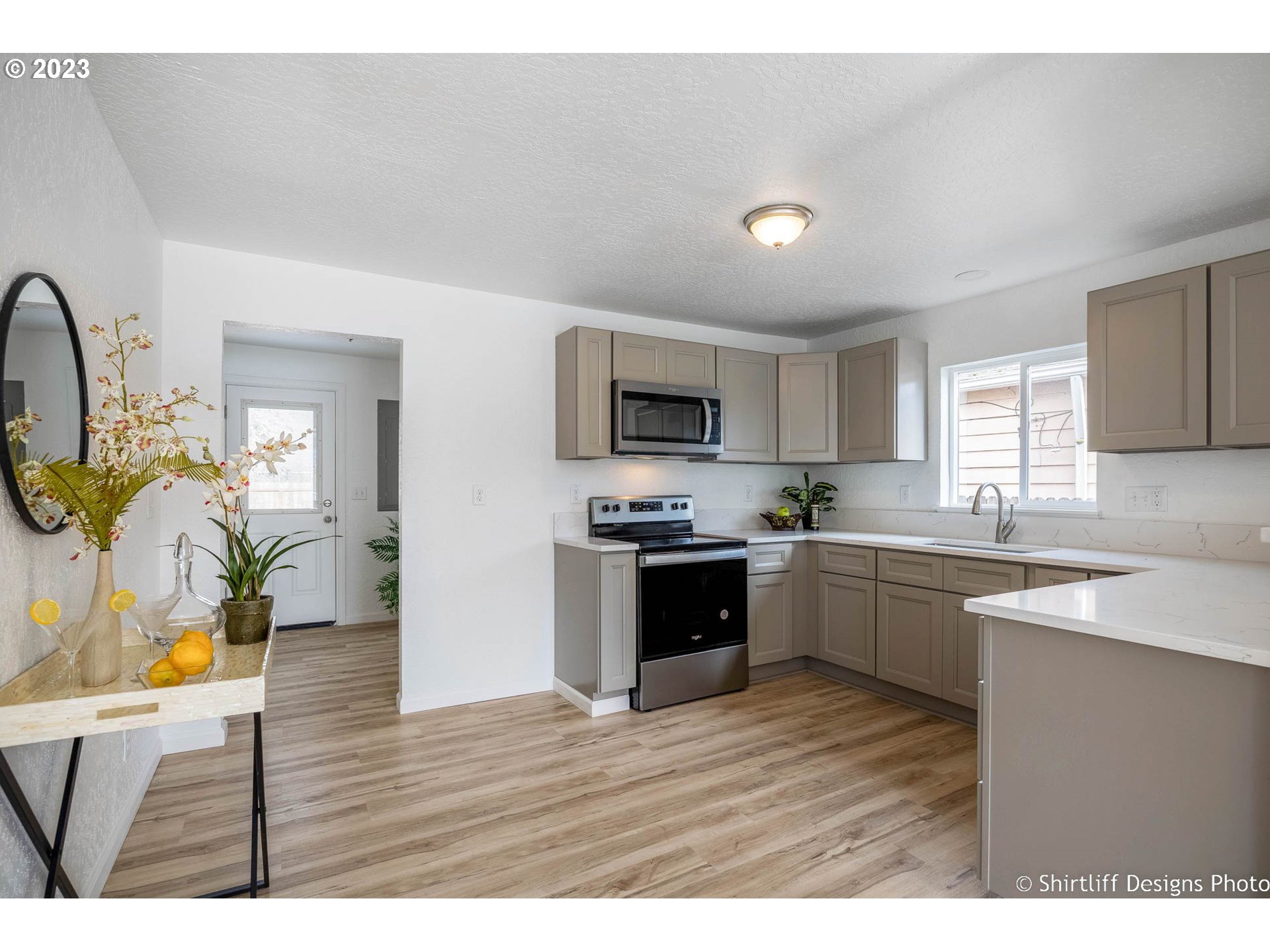 1446 E Street Springfield, OR 97477 - Photo 11 of 26 a kitchen with stainless steel appliances granite countertop a refrigerator a stove top oven a sink dishwasher and white cabinets with wooden floor