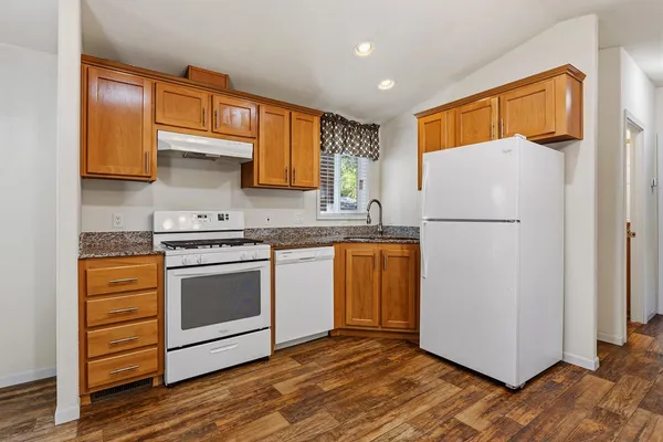a kitchen with granite countertop a refrigerator stove and sink