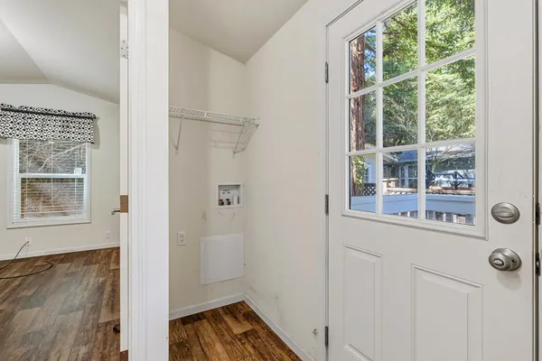 a view of an empty room with wooden floor and a window