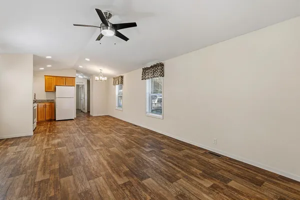 a view of empty room with wooden floor and ceiling fan