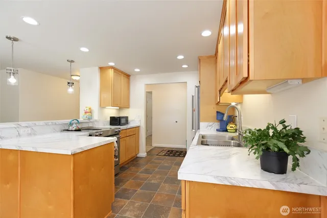 a kitchen with sink a refrigerator and potted plant
