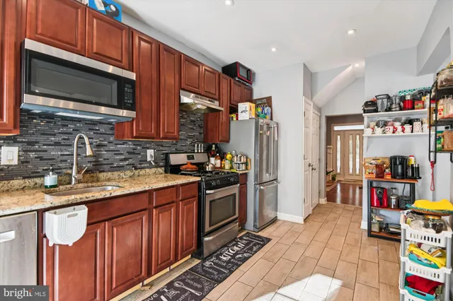 a kitchen with granite countertop lots of clutter and stainless steel appliances