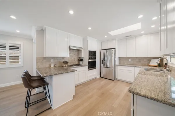 a kitchen with stainless steel appliances granite countertop a sink refrigerator and cabinets
