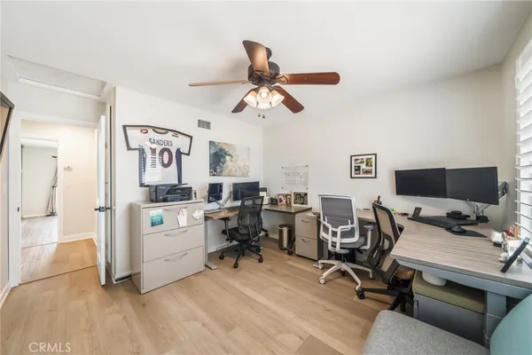a view of a workspace with furniture and a ceiling fan