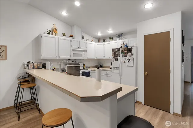 a kitchen with kitchen island a stove a refrigerator and a dining table with wooden floor