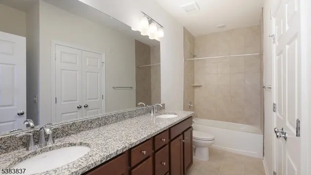a bathroom with a granite countertop double vanity sink and mirror with shower