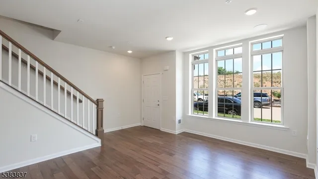 a view of an empty room with wooden floor and windows