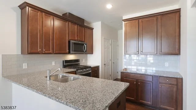 a kitchen with granite countertop wooden cabinets stainless steel appliances and a counter space