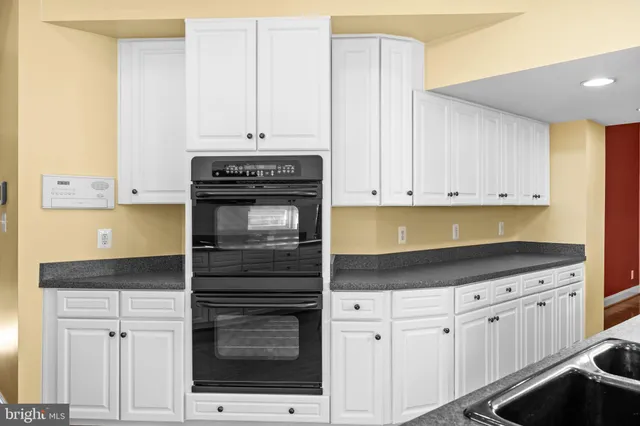 a kitchen with granite countertop white cabinets and stainless steel appliances