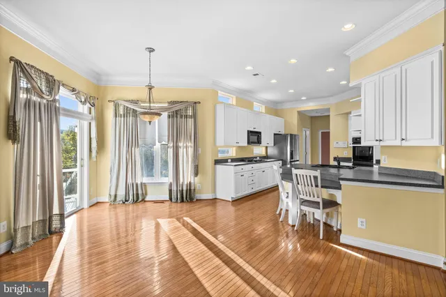 a open kitchen with stainless steel appliances granite countertop a refrigerator a stove top oven a sink dishwasher and white cabinets with wooden floor