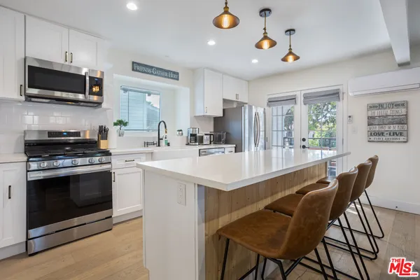 a kitchen with kitchen island a stove a sink a microwave and a dining table