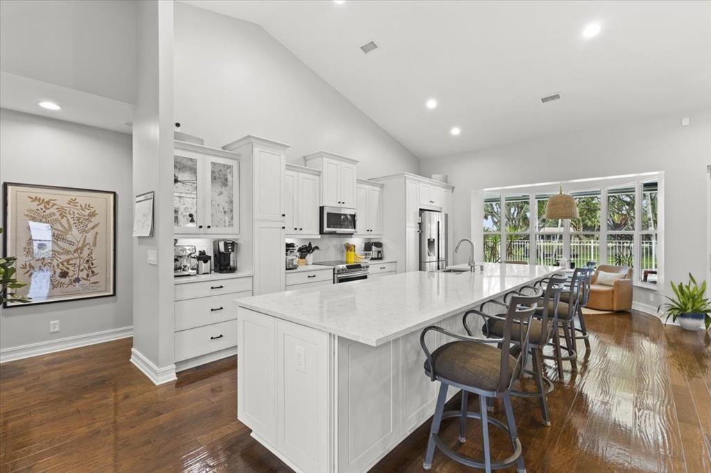 10349 Camelback Lane Boca Raton, FL 33498 - Photo 9 of 38 a large white kitchen with granite countertop a stove a sink a dining table and chairs