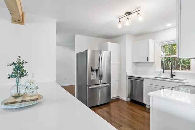 a kitchen with stainless steel appliances a refrigerator a sink a stove a dining table and chairs