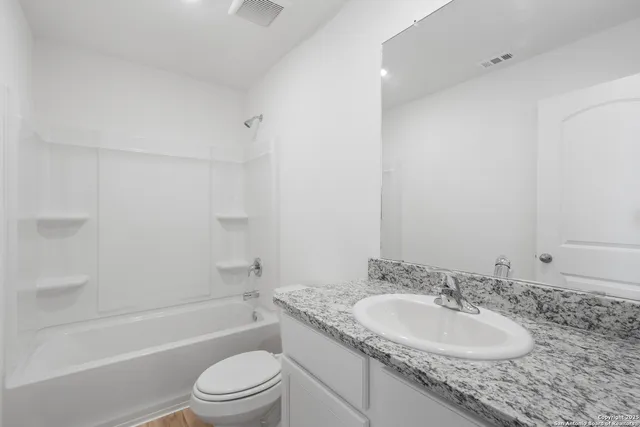 a bathroom with a granite countertop sink toilet and shower