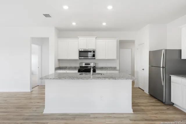 a large kitchen with stainless steel appliances granite countertop a refrigerator a sink a stove a microwave and wooden floor