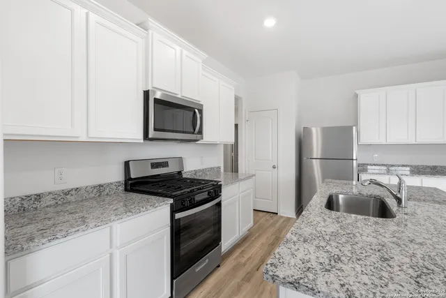 a kitchen with granite countertop a sink a stove and refrigerator