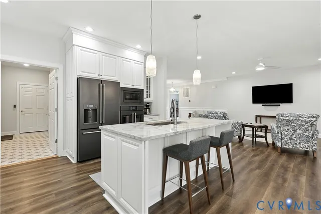 a kitchen with stainless steel appliances a stove a refrigerator a sink a dining table with chairs with wooden floor