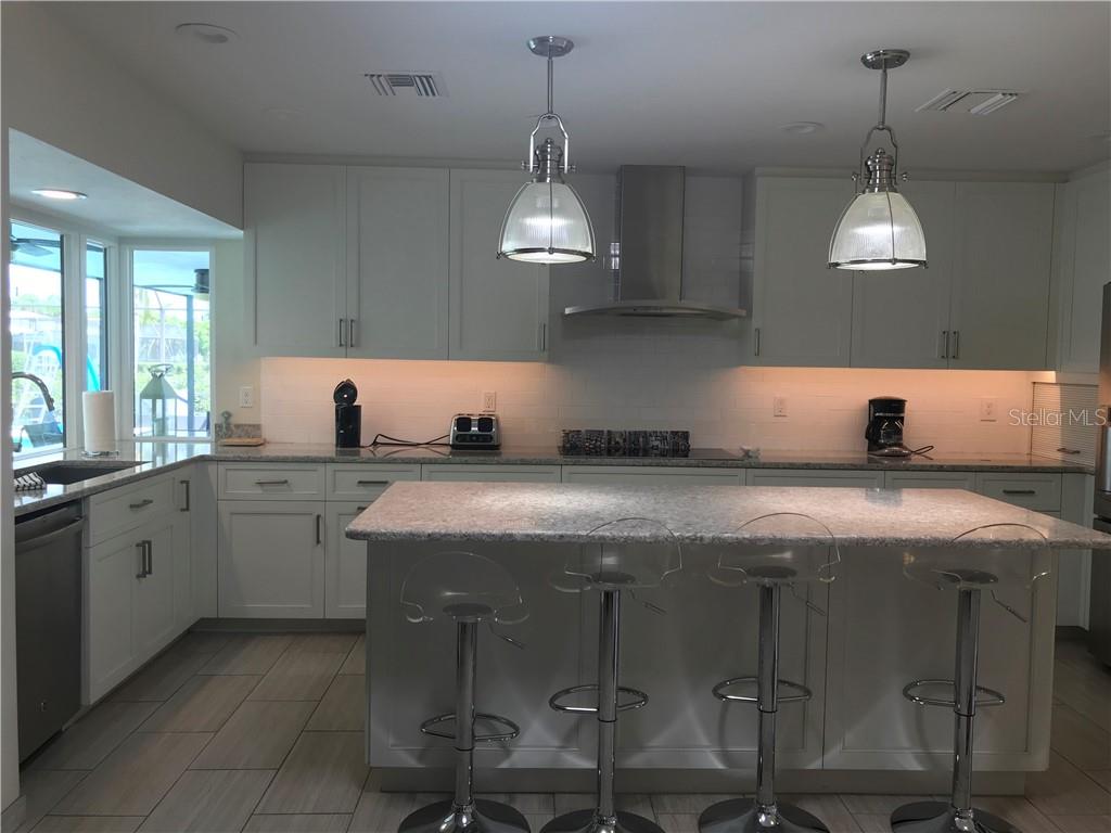 5519 Azure Way Sarasota, FL 34242 - Photo 3 of 25 a kitchen with stainless steel appliances granite countertop a stove a sink dishwasher a dining table and chairs with wooden floor